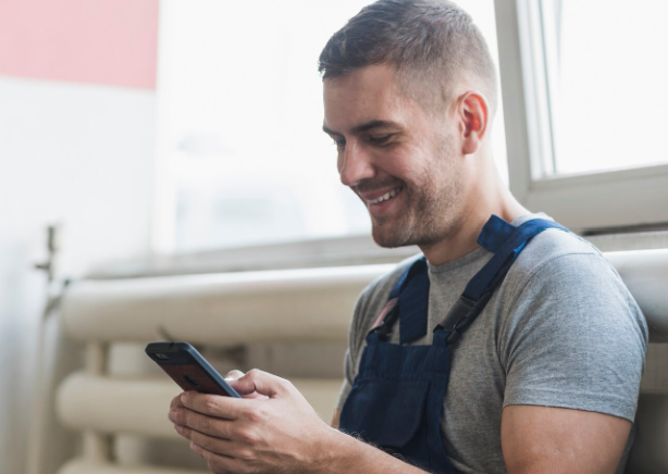 technicien homme souriant regardant son téléphone