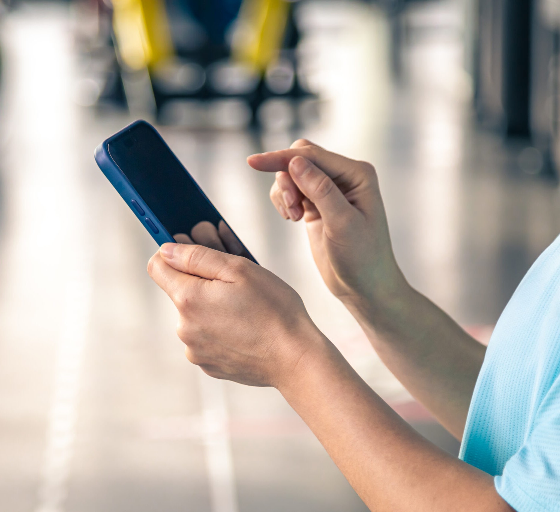 Woman using smartphone in fitness gym, close up.