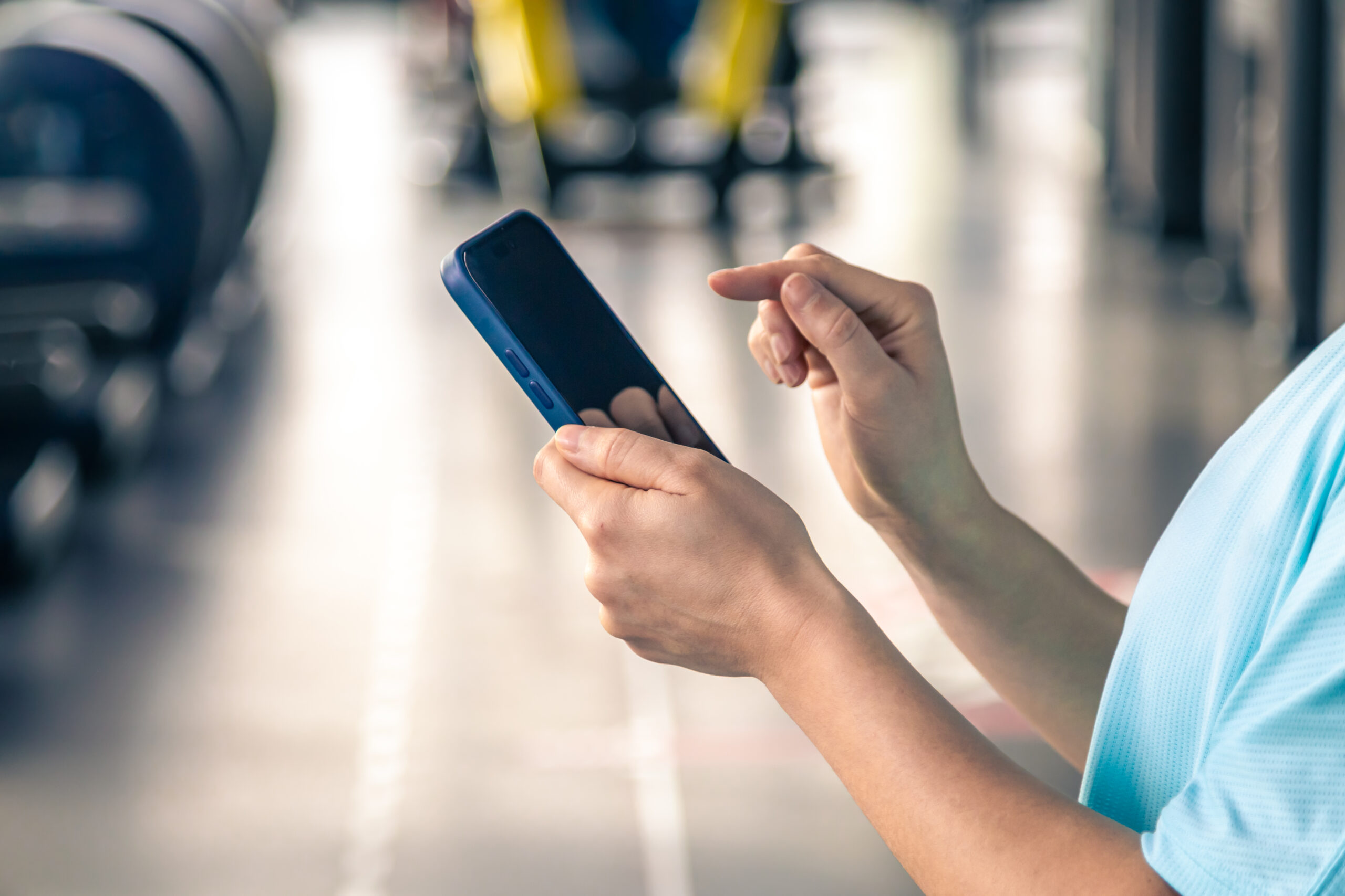 Woman using smartphone in fitness gym, close up.